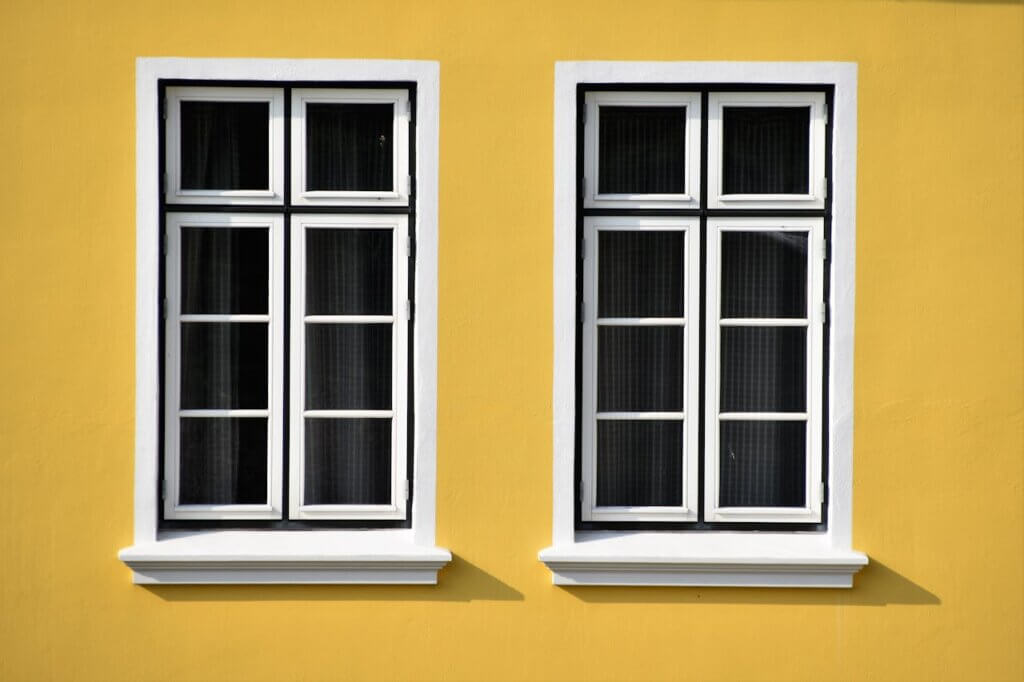 2 windows with a yellow wall